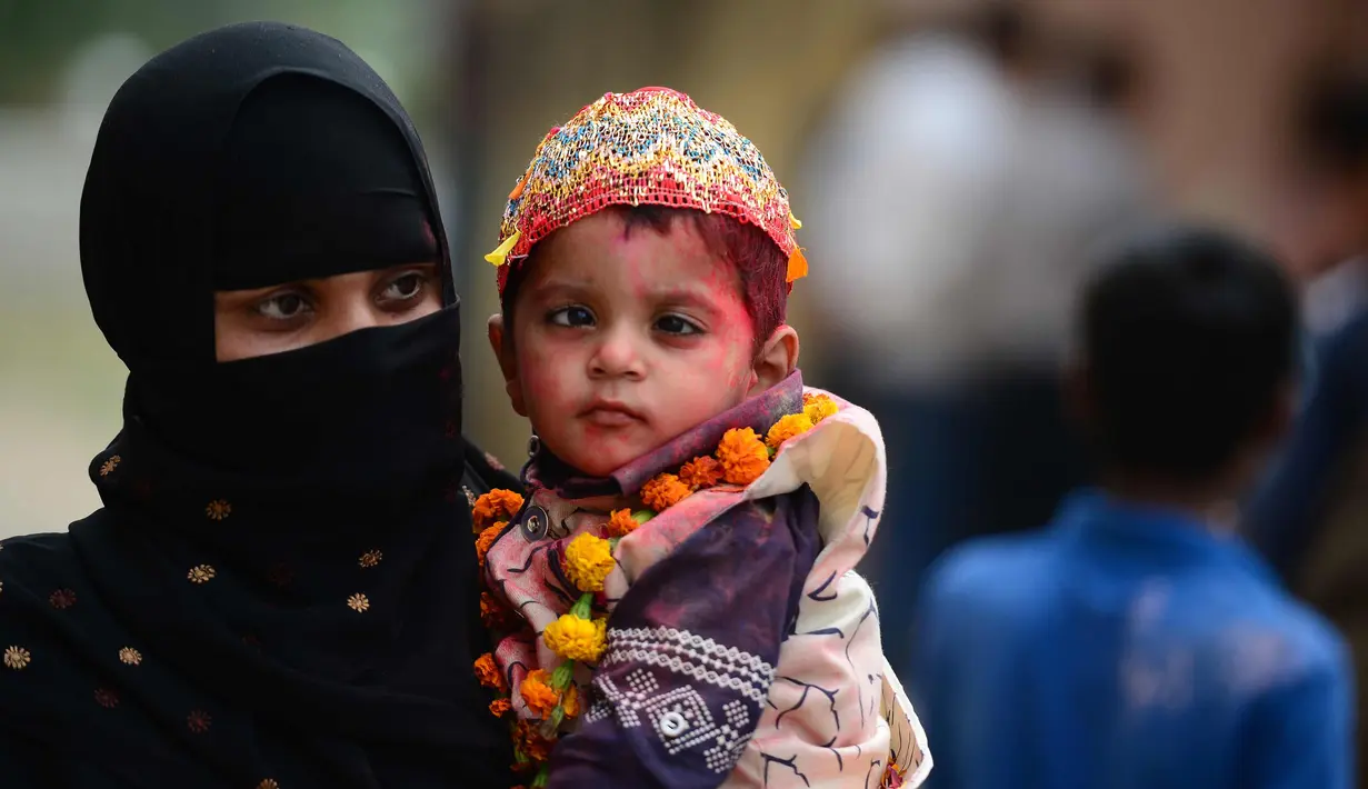 Seorang wanita Muslim India bersama anaknya yang menderita cerebral palsy ambil bagian dalam acara festival Hindu Holi untuk anak-anak dengan cerebral palsy yang diselenggarakan oleh Yayasan Trishla di Allahabad (25/2). (AFP Photo/Sanjay Kanojia)