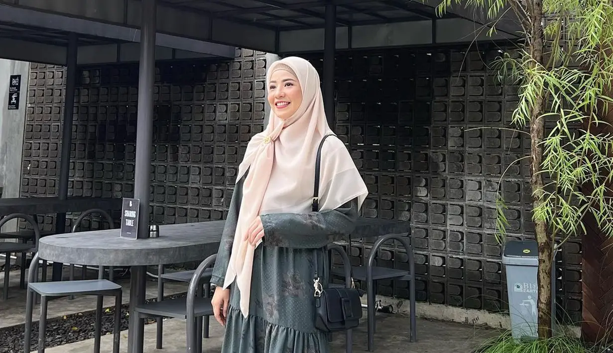 Ciptakan tampilan yang elegan dengan padu padan tiered dress warna gelap dan hijab warna cream cerah. [Foto: IG/natasharizkynew].