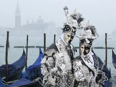 Dua orang peserta berpose di Piazza San Marco saat mengikuti Karnaval Venesia, Italia, Sabtu (30/1). Dalam acara tahunan ini, peserta mengenakan kostum ala Venesia abad ke-18 dan topeng-topeng unik menutupi wajah (REUTERS/Alessandro Bianchi)