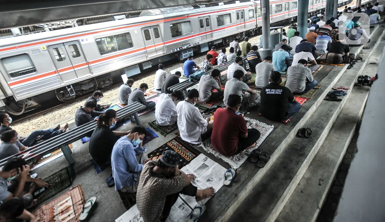 Kereta commuter line melintas dekat jemaah yang tengah salat Jumat di Stasiun Kampung Bandan, Jakarta, Jumat (7/5/2021). Sebagian jemaah menjadikan peron stasiun sebagai tempat salat dan sebagian lain berada di tangga serta jembatan penyeberangan. (merdeka.com/Iqbal S. Nugroho)