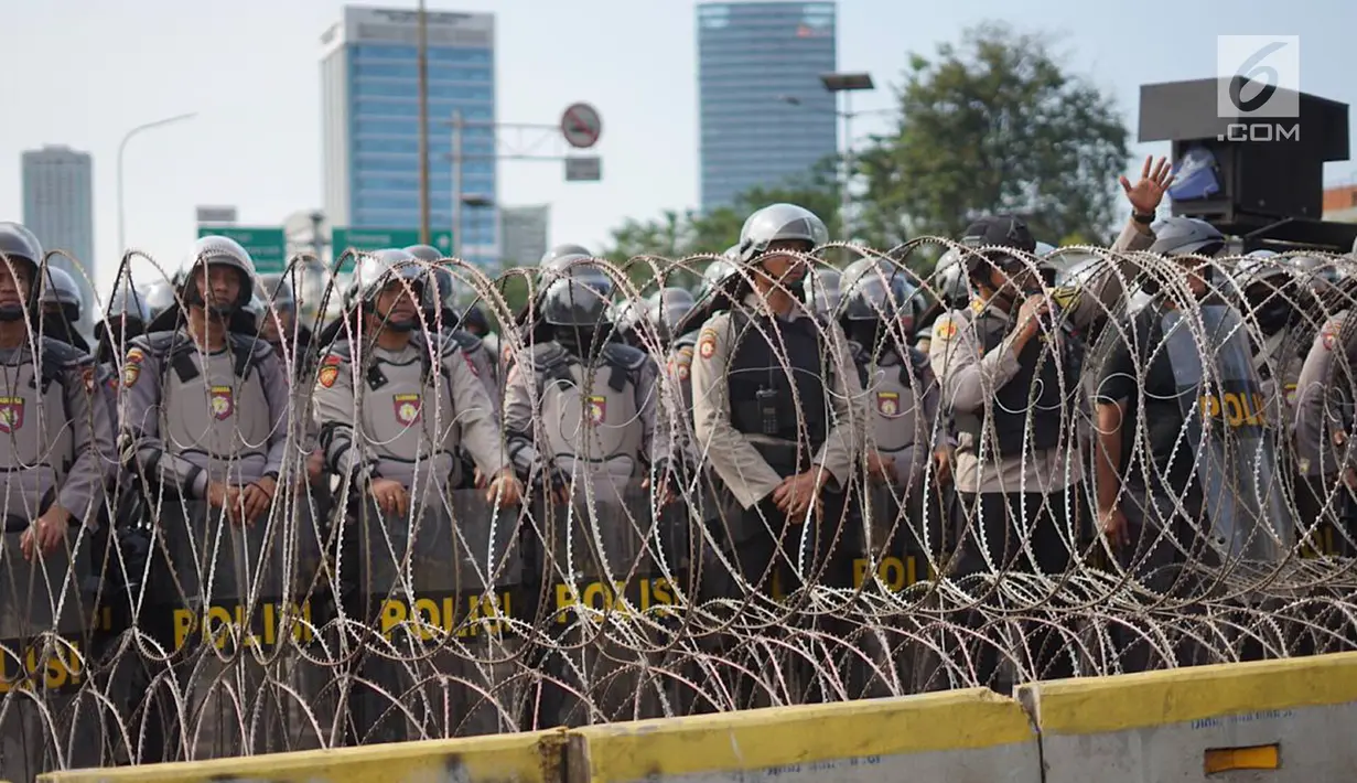 Aparat kepolisian berjaga di balik barikade kawat berduri saat unjuk rasa massa aksi dari elemen di depan Gedung DPR RI, Jakarta, Senin (30/9/2019). Aksi unjuk rasa tersebut menyikapi penolakan terhadap UU KPK dan sejumlah RUU yang dinilai bermasalah. (Liputan6.com/Immanuel Antonius)