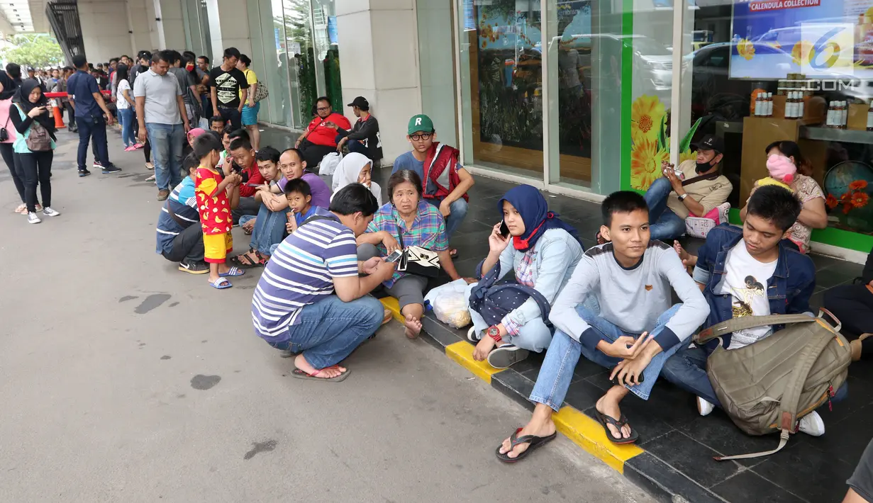 Ratusan calon pembeli duduk saat antre di depan Emporium Pluit Mall, Jakarta. Minggu (21/1). Mereka antre sejak mal belum dibuka untuk mendapatkan penawaran produk Xiaomi. (Liputan6.com/Fery Pradolo)