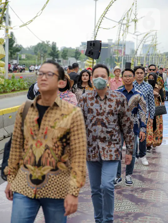 Sejumlah orang yang mengenakan batik berjalan di catwalk sepanjang Jalan Jenderal Sudirman, Jakarta, Minggu (2/10/2022). Kegiatan yang diikuti ratusan orang ini diselenggarakan oleh Bank Mandiri untuk menyambut Hari Batik Nasional yang jatuh setiap tanggal 2 Oktober 2022. (Liputan6.com/Faizal Fanani)