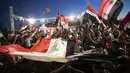 Pendukung mengibarkan bendera nasional dan foto Presiden Suriah Bashar Assad saat mereka merayakan kemenangannya di Omayyad Square, di Damaskus, Kamis (27/5/2021). Bashar al-Assad terpilih kembali untuk masa jabatan keempat sebagai presiden Suriah yang dilanda perang. (AP Photo/Hassan Ammar)