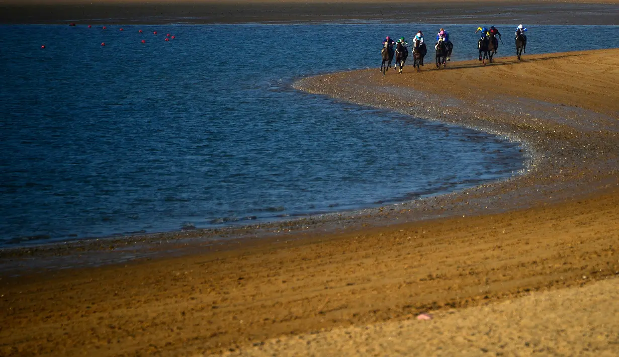 Peserta memacu kudanya saling balap di tepi pantai saat mengikuti lomba pacuan kuda pantai tahunan di Sanlucar de Barrameda, dekat Cadiz, Spanyol (17/8). Pacuan pertama digelar tahun 1845. (AFP Photo/Cristina Quicler)