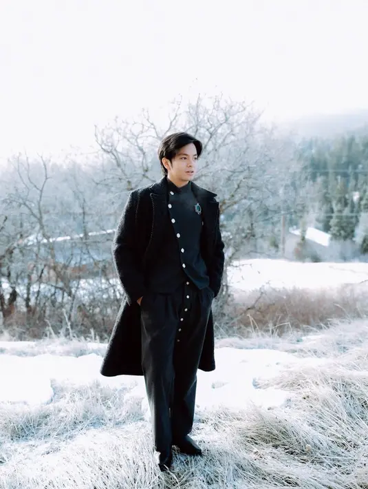 Saat di luar, Angga melapisi busananya dengan long coat hitam [@angga]