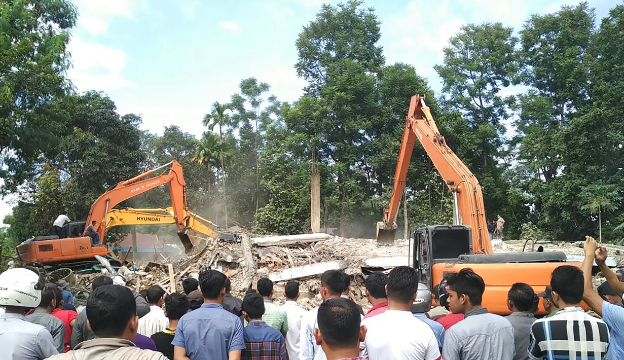 Warga menyaksikan evakuasi korban gempa 6,4 SR di Kabupaten Pidie Jaya, Aceh, Rabu (7/12). Kondisi terakhir ada 98 unit ruko roboh. Di Trienggadeng ada 15 rumah rusak berat," kata Puteh. (AFP PHOTO/Chaideer Mahyuddin)