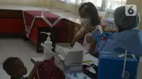 Seorang siswi SDN 01 dan SDN 03 Jatinegara Kaum melakukan vaksinasi anak usia 6-11 tahun di Jakarta Timur, Selasa (14/12/2021). Untuk wilayah Jakarta Timur 11 sekolah dasar di 10 kecamatan untuk awal vaksinasi Covid-19. (merdeka.com/Imam Buhori)