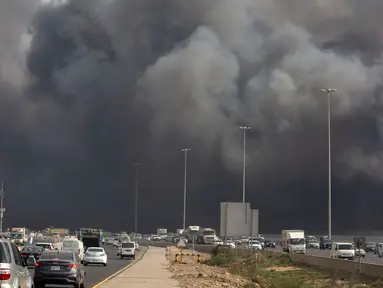Mobil-mobil melaju saat asap hitam  membumbung menyelimuti gedung Stasiun Kereta Api Cepat Haramain di kota Jeddah, Arab Saudi, Minggu (29/9/2019). Akibat kebakaran tersebut, setidaknya sepuluh orang terluka. (Photo by - / AFP)