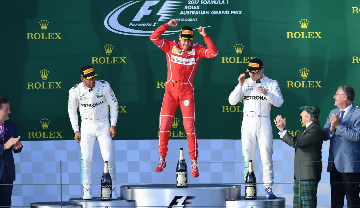 Pembalap Ferrari, Sebastian Vettel melompat merayakan kemenangannya di atas podium balapan GP Australia di Sirkuit Albert Park, Melbourne, Minggu (26/3). Ini merupakan kemenangan pertama Vettel bersama Ferrari sejak GP Singapura 2015. (WILLIAM WEST/AFP)