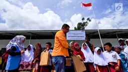 Perwakilan United Tractors memberikan paket peralatan sekolah kepada siswa korban gempa dan tsunami Palu dan Donggala di Balaroa, Sulteng, (16/11). United Tractors telah menyelesaikan pembangunan 4 sekolah sejak bulan Oktober. (Liputan6.com/HO/Eko)