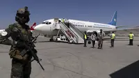 Seorang tentara Taliban berjaga-jaga ketika penumpang turun dari Kandahar, di Bandara Internasional Hamid Karzai di Kabul, Afghanistan, Minggu (5/9/2021). Bandara tersebut kembali dibuka untuk penerbangan domestik. (AP/Wali Sabawoon)