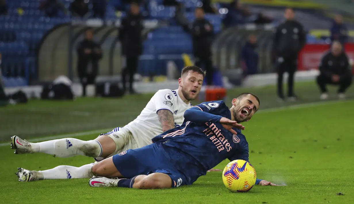 Pemain Arsenal Dani Ceballos (depan) jatuh di depan pemain Leeds United Liam Cooper pada pertandingan Liga Premier Inggris di Stadion Elland Road, Leeds, Inggris, Minggu (22/11/2020). Pertandingan berakhir dengan skor 0-0. (Molly Darlington/Pool Via AP)