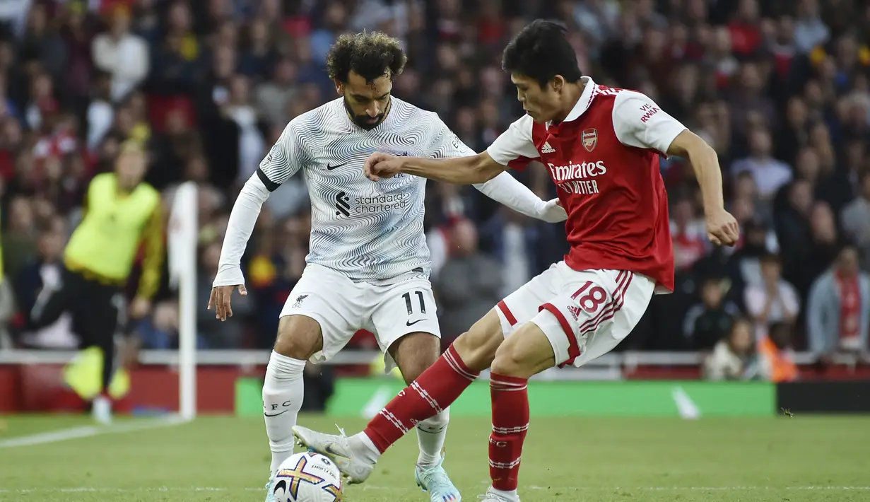 Penyerang Liverpool, Mohamed Salah berusaha melewati bek Arsenal, Takehiro Tomiyasu selama pertandingan lanjutan Liga Inggris di Stadion Emirates di London, Minggu (9/10/2022). Kemenangan Arsenal membuat tim Meriam London kembali ke puncak klasemen dengan koleksi 24 poin. (AP Photo/Rui Vieira)
