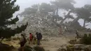 Sejumlah wisatawan berjalan di depan patung Notre Dame des Neiges di hutan Bavella, Prancis, Rabu (25/8/2021). Situs wisata alam Bavella dipenuhi oleh pengunjung selama musim panas. (AFP/Pascal Pochard-Casabianca)