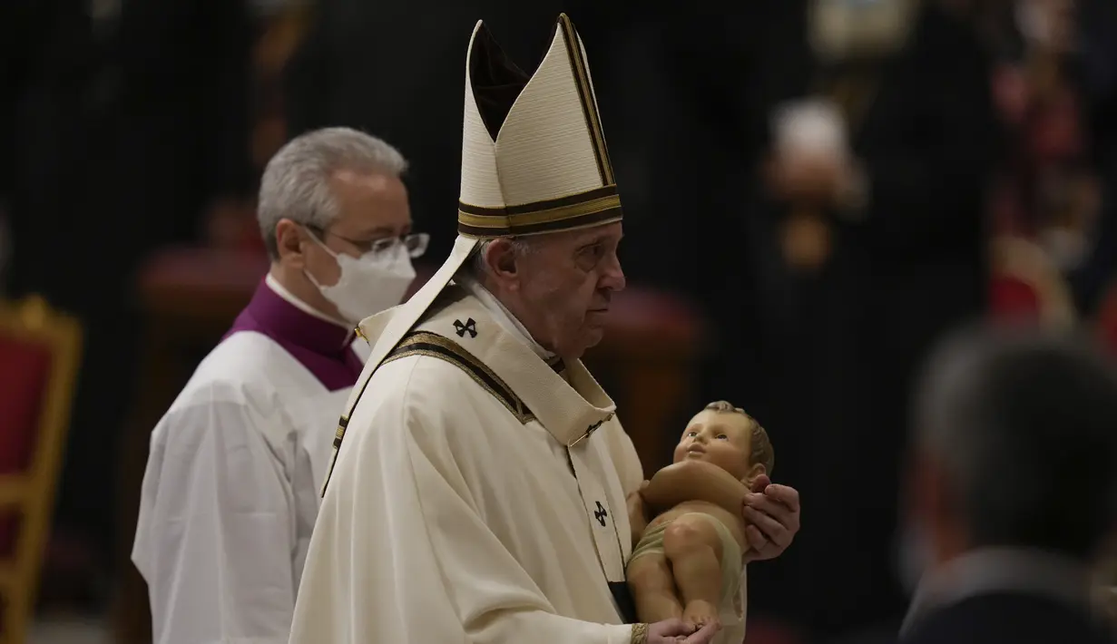 Paus Fransiskus memegang patung Bayi Yesus saat ia merayakan Misa Malam Natal, di Basilika Santo Petrus, di Vatikan, Jumat (24/12/2021). Di acara tersebut, Paus Fransiskus mengatakan meskipun ada kebangkitan kasus COVID-19 yang telah mendorong mandat vaksin baru untuk karyawan Vatikan. (AP Photo/Ale