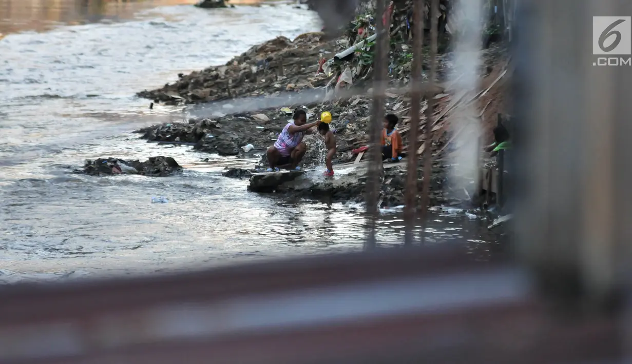 Warga memandikan anaknya di bantaran Kali Ciliwung, Jakarta, Senin (19/11). Tak adanya akses sanitasi yang layak menyebabkan anak-anak menderita stunting. (Merdeka.com/Iqbal Nugroho)