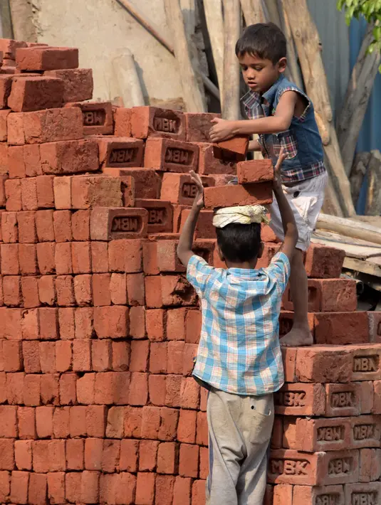 Dua orang anak mengangkat batu batu di sebuah bangunan New Delhi, India, Minggu (19/11). Setengah dari seluruh pekerja anak-anak melakukan pekerjaan yang dianggap berbahaya serta tidak ada kontrak kerja dan jaminan sosial. (DOMINIQUE FAGET)