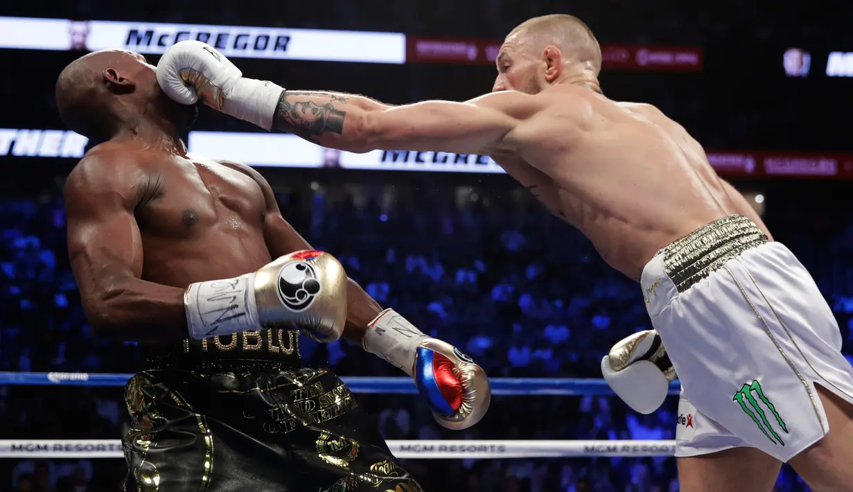 Conor McGregor melakukan pukulan tepat diwajah Floyd Mayweather dalam pertandingan tinju super kelas welter di Las Vegas (26/8). (AP Photo/Isaac Brekken)