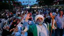 Pria berpakaian Ottoman berfoto dengan latar belakang umat Muslim yang berbuka puasa di Sultanahmet Square, Istanbul, 27 Mei 2017. Turki memiliki tradisi Meja Bumi, jamuan makan malam Ramadan guna merayakan puasa hari pertama (AP Photo/Lefteris Pitarakis)