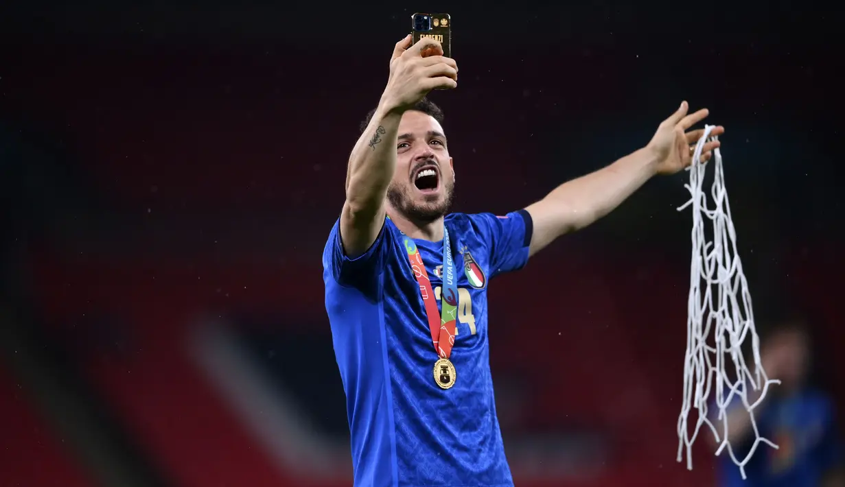 Alessandro Florenzi memamerkan potongan jaring gawang Stadion Wembley lewat ponselnya usai Italia menangkan pertandingan Final Euro melawan Inggris. (Foto: AP/Pool/Laurence Griffiths)
