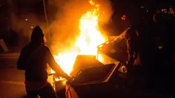 Pengunjuk rasa membakar tempat sampah selama aksi protes berujung kerusuhan di Aulnay-sous-Bois, pinggiran utara kota Paris, Rabu (8/2). Ketegangan tersebut dipicu dugaan penganiayaan dan pemerkosaan oleh seorang polisi terhadap seorang tahanan. (AFP)