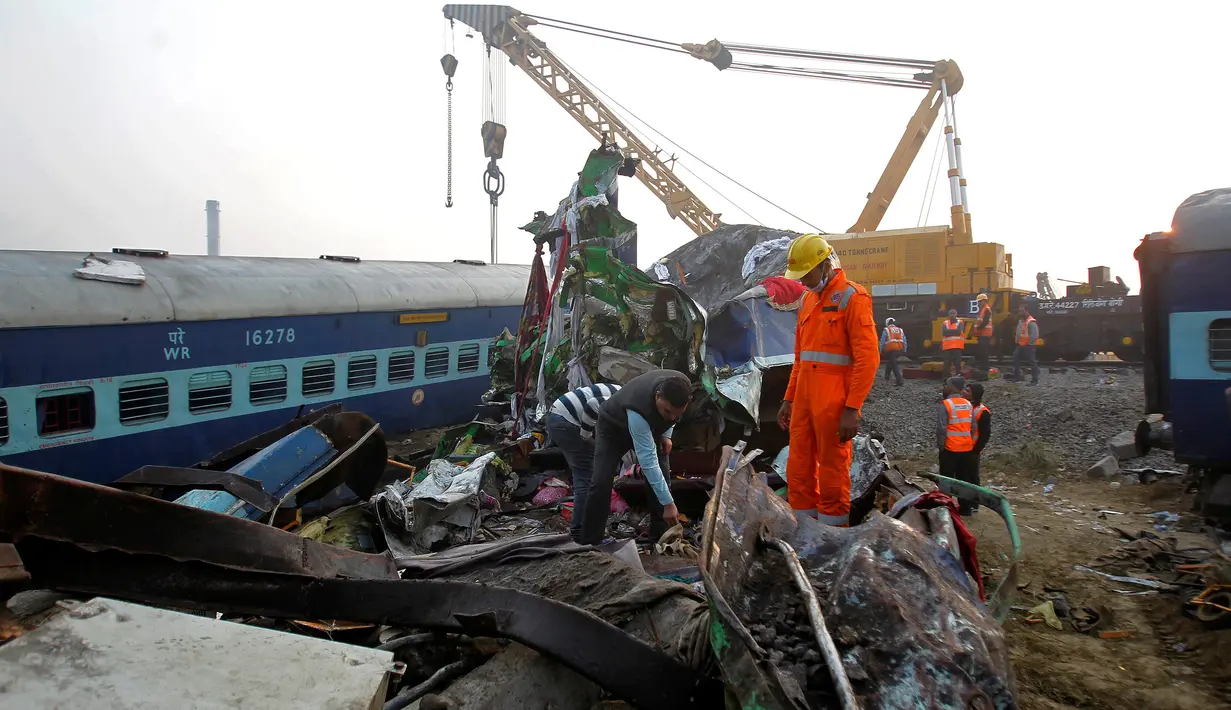 Petugas penyelamat mencari korban di antara bangkai kereta api setelah terjadi kecelakaan di Pukhrayan, Kanpur, India (21/11). Kebanyakan korban terjebak karena masih tertidur saat kereta mengalami kecelakaan pada pagi hari. (Reuters/ Jitendra Prakash)