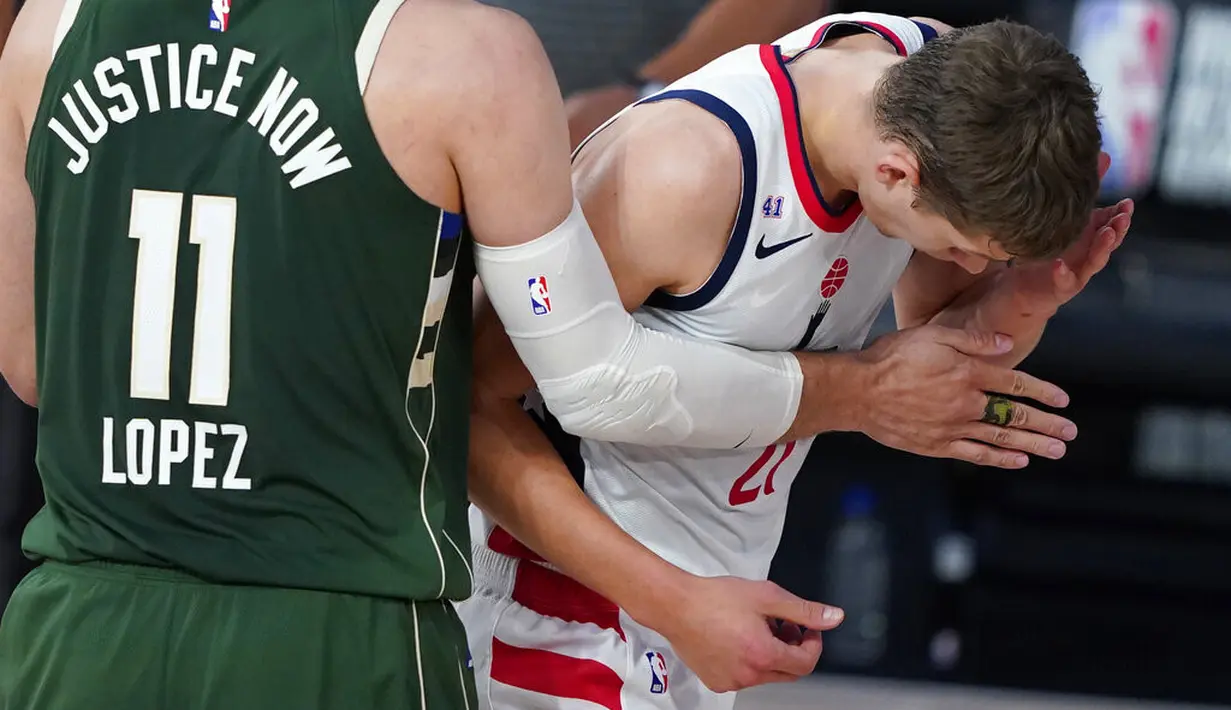 Pebasket Washington Wizards, Moritz Wagner, memgang wajahnya usai ditanduk pebasket Milwaukee Bucks, Giannis Antetokounmpo, pada laga NBA, Selasa (11/8/2020). Bucks mengalahkan Wizards dengan skor 126-113. (AP Photo/Ashley Landis, Pool)