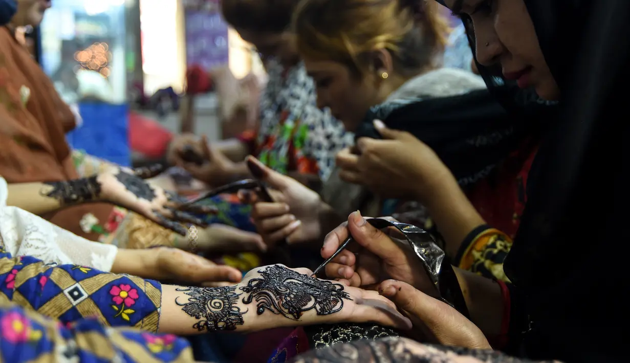 Sejumlah wanita Pakistan membuat henna dengan pacar di salon kecantikan menjelang Hari Raya Idul Fitri di Karachi (3/6/2019). Umat Muslim di seluruh dunia sedang bersiap untuk merayakan Hari Raya Idul Fitri, yang menandai akhir bulan puasa Ramadan. (AFP Photo/Asif Hassan)