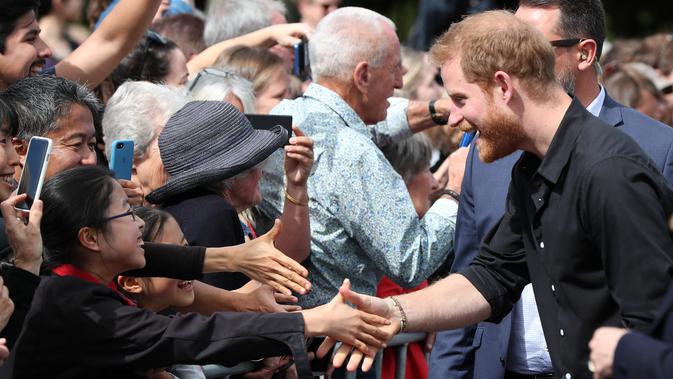 Pangeran Harry tertawa saat menyalami anak kecil di Taman Pemerintah Rotorua, Selandia Baru, Rabu (31/10). Pangeran Harry dan Meghan Markle sedang dalam tur tiga minggu di Australia, Selandia Baru, Tonga, dan Fiji. (Michael Bradley/Pool/AFP)