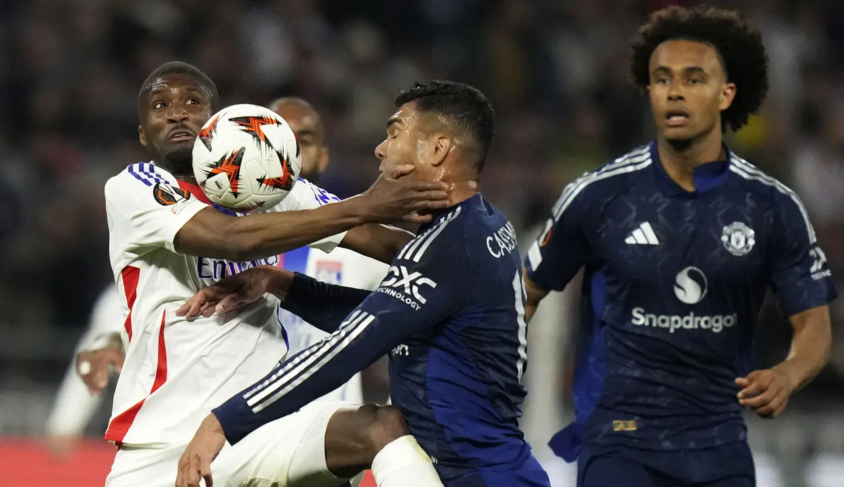 Pemain Manchester United, Casemiro (kanan) berebut bola dengan pemain Lyon, Clinton Mata dalam laga leg 1 perempat final Liga Europa 2024/2025 di Parc Olympique Lyonnais Groupama stadium, Decines-Charpieu, Prancis. (AP Photo/Thibault Camus)