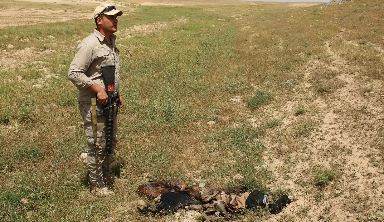 Seorang Tentara Irak berdiri di dekat mayat orang tak dikenal saat melihat terowongan bawah tanah buatan ISIS di sebuah desa di Har Bardun, Irak, Kamis (28/4). (REUTERS/Goran Tomasevic) 