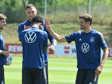 Pemain Jerman Thomas Mueller (kanan) bercanda dengan rekan setimnya saat sesi latihan di pusat olahraga BVSC, Budapest, Hungaria, 13 Juni 2022. Jerman akan menghadapi Italia pada pertandingan sepak bola UEFA Nations League. (Attila KISBENEDEK/AFP)