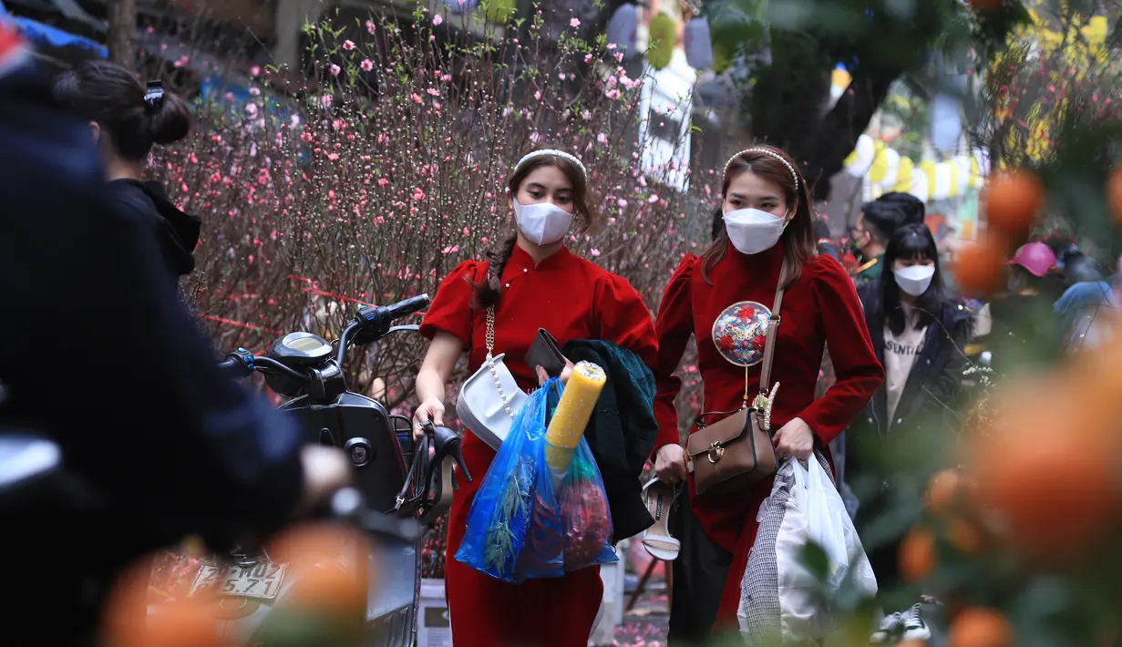 Dua wanita berbelanja di pasar "Tet" Tahun Baru Imlek tradisional di kawasan tua Hanoi, Vietnam, Jumat (28/1/2022). Vietnam merayakan Tahun Baru Imlek yang akan datang di tengah peringatan terhadap perjalanan dan pertemuan besar karena COVID -19. (AP Photo/Hau Dinh)