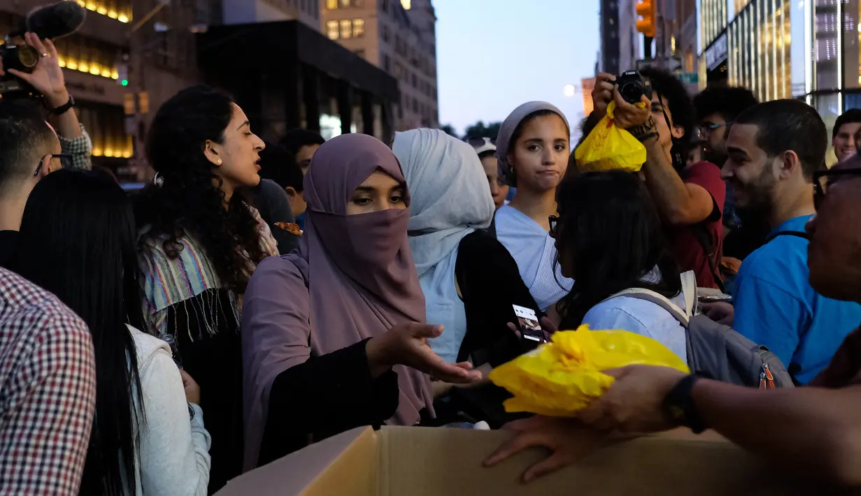 Relawan membagikan makanan berbuka puasa untuk umat muslim dan aktivis pendukung antaragama di dekat Trump Tower, New York, Kamis (1/6). Ratusan muslim menggelar demonstrasi memprotes retorika dan kebijakan Donald Trump yang xenophobia. (Jewel SAMAD/AFP)