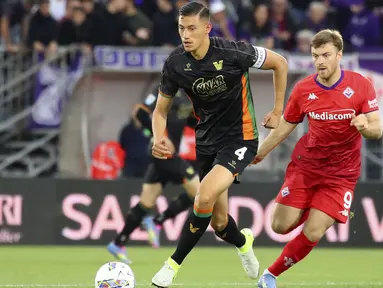 Pemain Venezia, Jay Idzes (kiri) menggiring bola melewati pemain Fiorentina dalam laga lanjutan Liga Italia 2024/2025 di Stadio Pier Luigi Penzo, Venezia, Italia, Senin (12/05/2025) waktu setempat. (AP Photo/LaPresse/Paola Garbuio)