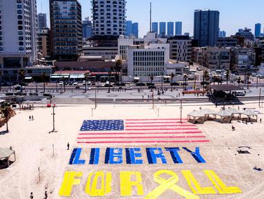 Foto udara yang diambil pada Jumat 4 Juli 2025 menunjukkan instalasi pasir yang menggambarkan bendera Amerika Serikat (AS) dan slogan “Liberty for All” atau Kebebasan untuk Semua di salah satu pantai di luar kantor cabang Kedutaan Besar (Kedubes) Amerika Serikat (AS) di Tel Aviv, Israel. (Jack GUEZ/AFP)