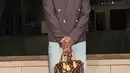 Pharrell William mengenakan blazer oversize dipadukan celana denim flare. Sambil membawa mini bag dari Louis Vuitton. [Louis Vuitton]