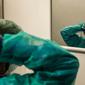 Seorang perawat mengenakan peralatan kerjanya untuk memulai shift di rumah sakit Cremona, tenggara Milan, Lombardy, 12 Maret 2020. Para pekerja kesehatan Italia kelelahan setelah selama bermingu-minggu mereka yang berada di garda terdepan memerangi pandemi virus corona. (Paolo MIRANDA/AFP)