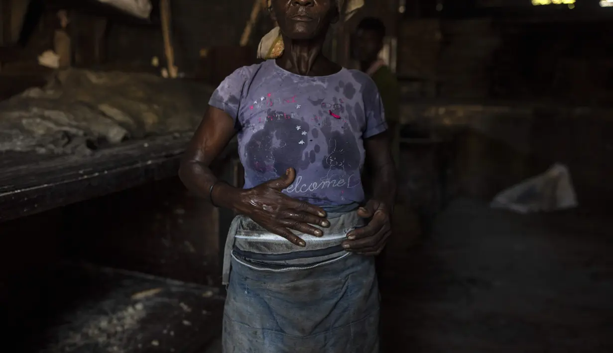 Seorang wanita yang bertugas memuat air ke dalam ember untuk membuat adonan berbicara kepada para pekerja di dalam toko roti Bongu di lingkungan Bel Air di Port-au-Prince, Haiti, Senin (27/9/2021).  (AP Photo/Rodrigo Abd)