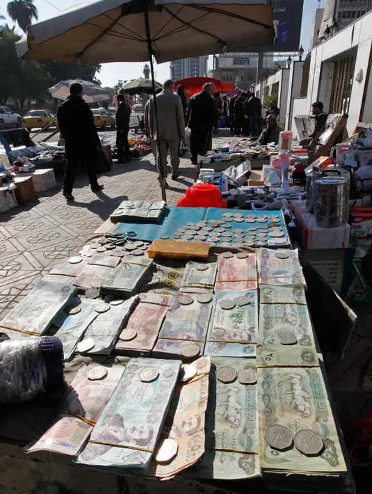 Suasana sebuah pasar yang menjual uang kertas Irak yang bergambar mantan Presiden Irak, Saddam Hussein di Baghdad, Irak (28/12). Pada tahun 2003 mata uang yang bergambar Saddam Hussein ini diganti dengan mata uang Dinar Irak yang baru. (AFP/Sabah Arar)