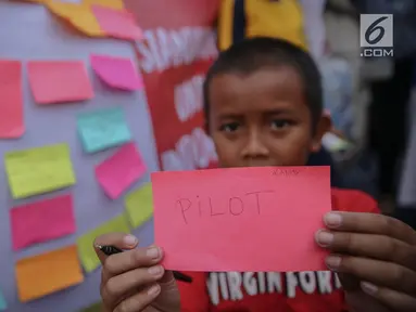 Seorang anak menunjukan tulisan cita-citanya  di jalur banjir kanal barat Tanah Abang, Jakarta, Senin (31/7). Kegiatan tersebut sebagai bentuk harapan mereka dalam rangka peringati hari anak nasional. (Liputan6.com/Faizal Fanani)