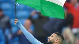 Gelandang Manchester City, Riyad Mahrez mengibarkan bendera Palestina saat merayakan timnya meraih gelar Liga Inggris di stadion Etihad, Minggu (23/5/2021). Pada 10 Mei lalu, Mahrez memposting foto bendera Palestina di akun media sosialnya. (AFP Photo/Pool/Dave Thompson)