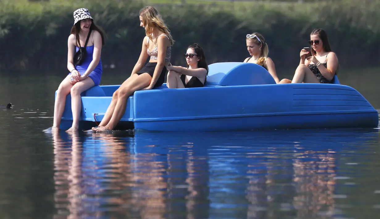 Sejumlah wanita bersantai di perahu kayuh di The Serpentine di Hyde Park di London, Rabu, (12/8/2020). Peringatan badai masih berlaku untuk sebagian besar Inggris pada hari Rabu, sementara suhu tinggi diperkirakan lagi di banyak bagian Inggris. ( AP Photo / Kirsty Wigglesworth)