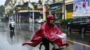 Pejalan kaki yang mengenakan jas hujan mengendarai sepeda saat hujan deras di Hanoi (14/10/2020). Badai tropis Nangka menghantam Vietnam tengah-utara yang mengakibatkan bencana alam, terutama hujan lebat dan banjir, telah menyebabkan 28 orang tewas dan 12 lainnya hilang. (AFP Photo/Manan Vatsyayana)