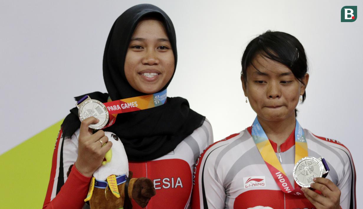 Pebalap sepeda Indonesia, Sri Sugiyanti dan Ni'mal Maghfiroh, saat pembagian medali pada Asian Para Games di Velodrome, Jakarta, Kamis (11/10/2018). Pasangan ini meraih medali perak di nomor trek Individual Pursuit B putri. (Bola.com/M Iqbal Ichsan)
