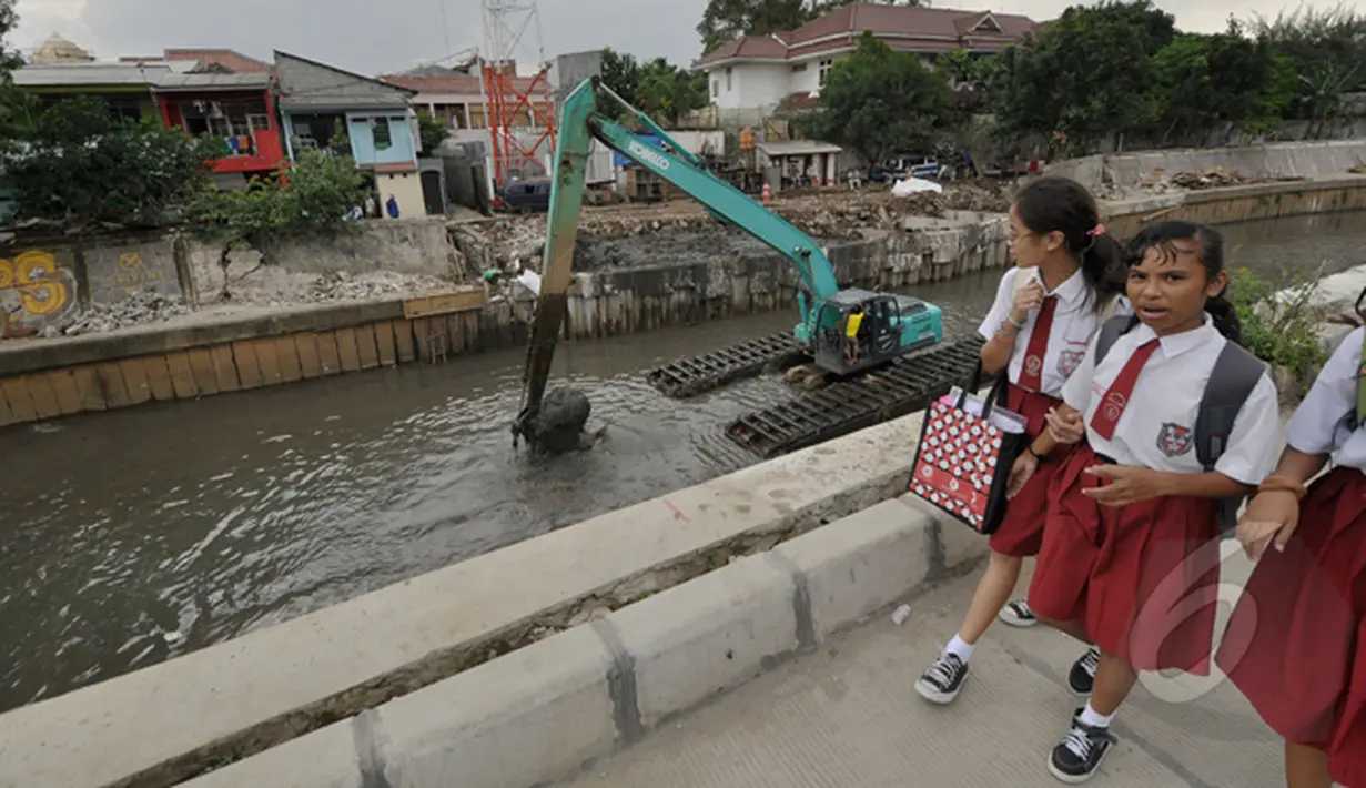 Sejumlah siswa SD berjalan di dekat pengerukan lumpur kali inspeksi Ciliwung, Jakarta, Selasa (3/3/2015). Pengerukan dilakukan untuk menjaga sungai tetap baik dan lancar. (Liputan6.com/Faizal Fanani)