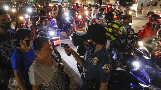Polisi memeriksa suhu tubuh warga di pos pemeriksaan virus corona COVID-19 di Manila, Filipina, Senin (16/3/2020). Polisi beserta petugas lalu lintas dan petugas desa melakukan pengecekan suhu tubuh warga untuk mencegah penyebaran virus corona COVID-19. (AP Photo/Aaron Favila)