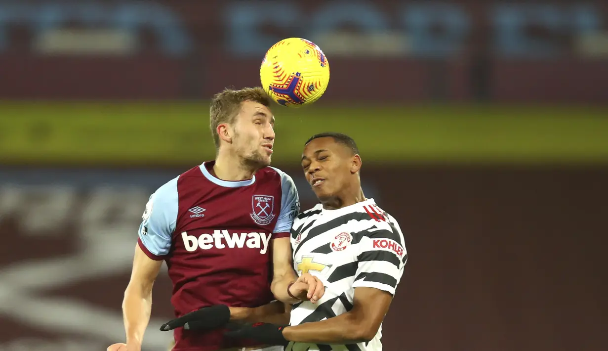 Penyerang Manchester United, Anthony Martial berebut bola udara dengan gelandang West Ham, Tomas Soucek pada pertandingan lanjutan Liga Inggris di stadion London di London, Inggris, Minggu (6/12/2020). MU menang 3-1 atas West Ham. (Julian Finney/Pool Via AP)
