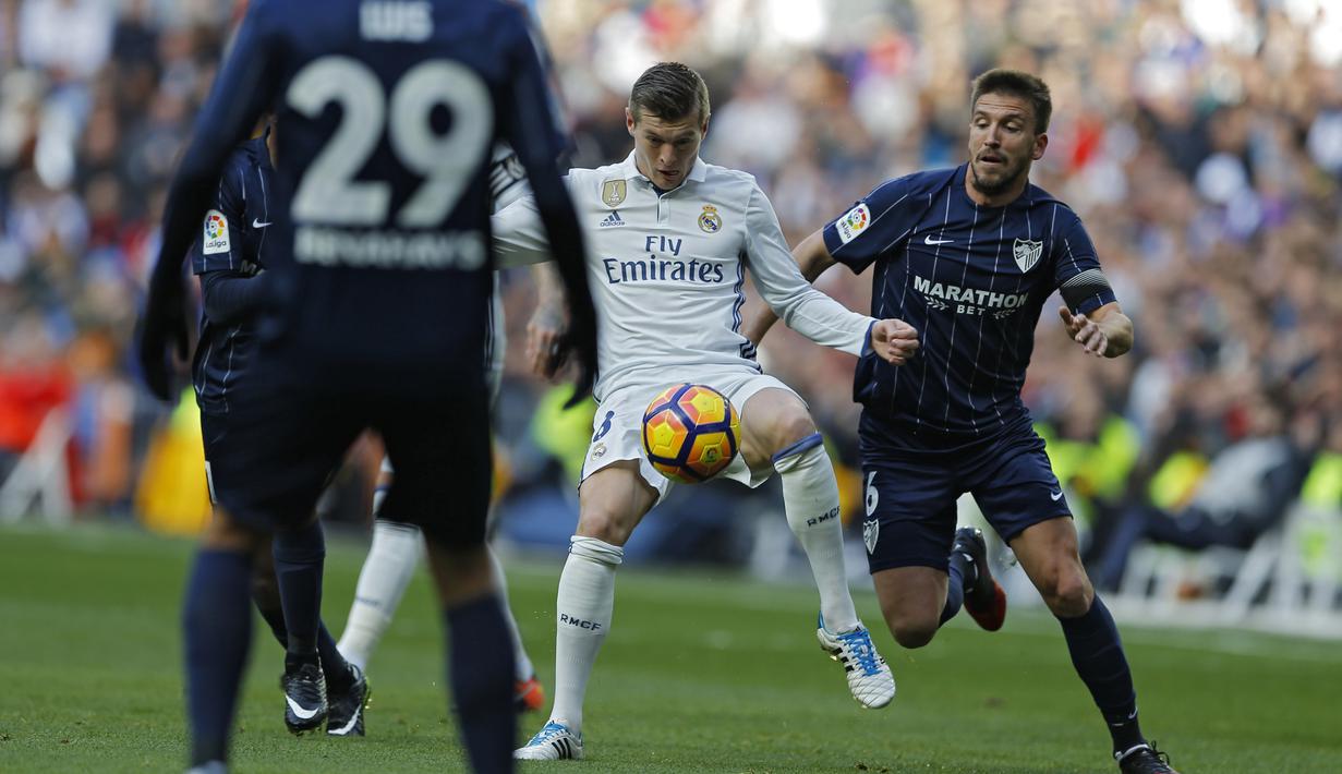 Toni Kroos (tengah) berusaha menerobos ketatnya pertahanan Malaga pada lanjutan La Liga di Santiago Bernabeu stadium, Madrid, Sabtu (21/1/2017). Madrid menang 2-1. (AP/Francisco Seco)